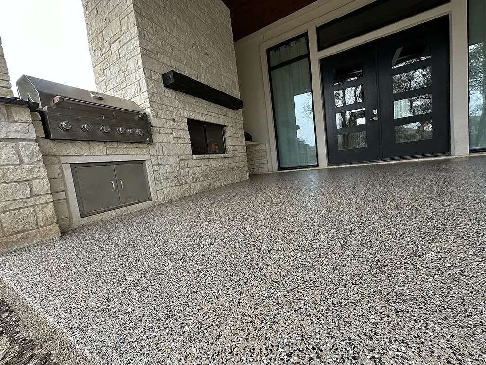 Covered patio with a stone fireplace and a coated floor